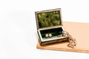 A silver-toned jewelry box with green marbled interior displaying diamond-studded star earrings in an art gold jewelry article