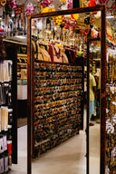 A rustic wooden framed mirror reflecting rows of gold jewelry bangles displayed on a grid for fine jewelry gifts