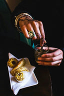 Elegant gold henna hand holding silver spoon over glass
