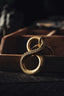 a pair of gold rings sitting on top of a wooden box