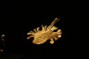 Gold jewelry ancient mask with intricate facial features and radiating prongs highlighting fine art gold jewelry symbolism
