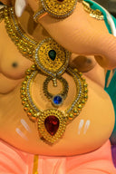 A gold-plated art deco necklace featuring intricate filigree and a red teardrop gemstone in fine jewelry design