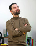 A man wearing a brown turtleneck sweater with gold jewelry exemplifies fine jewelry in david yurman style.