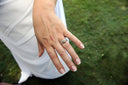 A sparkling diamond engagement ring with a silver-toned band worn on a hand complements men’s gold rings styles.