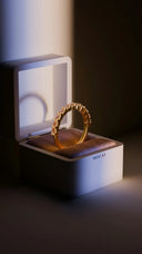 A gold eternity band ring with sparkling diamonds in a white mirai jewelry box for gold engagement rings.