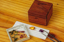 A polished amber teardrop gemstone displayed with colorful stones and tweezers in an everett jewelry store case