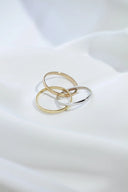 Three interlocking gold rings in 14k gold and silver tones crafted from polished metal for modern gold jewelry styling.