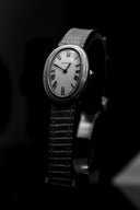 Silver oval cartier watch with white dial roman numerals and textured leather strap in article on 18k gold jewelry artistry