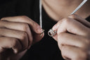 Silver-toned fine jewelry pendant with an intricate crown motif and small embedded stones for heirloom care tips
