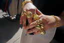 A hand wearing multiple gold-toned sculptural rings and a matching chain bracelet showcasing art gold jewelry.