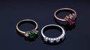 Three gold-toned birthstone jewelry rings with emerald ruby and sapphire gemstones and diamond accents for engagement rings.