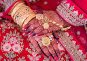 Gold floral ring with central red gemstone on henna-decorated hand showcasing art gold jewelry creativity.