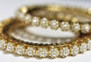 Gold bangle in 18k gold adorned with white pearls in a floral pattern featured in gold jewelry care tips article