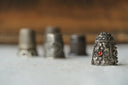 Silver thimble with intricate floral engraving and central red gemstone featured in engagement rings at everett jewelry store