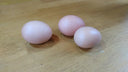 Three pale pink Fabergé eggs on light wood, evoking royal jewels