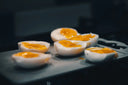Sliced Fabergé eggs with runny yolks on dark board