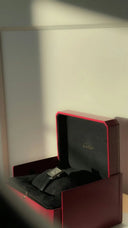 A sleek black leather strap watch with rectangular silver case in a red cartier box complements fine jewelry and art gold styles