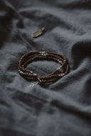 Bracelet and feather jewelry on a gray cloth.