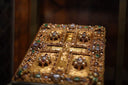 Gold ornate reliquary box with intricate gemstone inlays and detailed religious iconography in fine jewelry art gold jewelry style