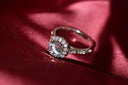 A sparkling diamond engagement ring with a central round stone on a silver band in fine jewelry and gold jewelry context