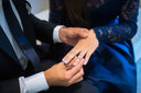 A delicate silver engagement ring with a central diamond worn on a woman’s finger in a van cleef style.