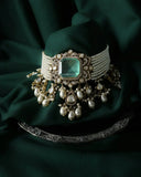 An ornate choker necklace with a central emerald green gemstone set in ethical gold with pearls and diamonds for luxury jewelry.