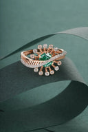 A rose gold handmade gold jewelry ring with a central emerald and diamonds featured in fine jewelry massachusetts article