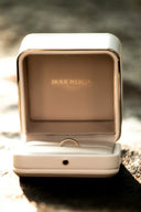 A delicate gold-toned beaded ring inside an elegant white box from Boucherons fine jewelry collection.