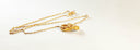 Gold-colored chain necklace with ornate textured pendant featuring intricate detailing in 18k gold jewelry trends.