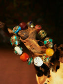 Jeweled bracelet displayed on a wooden branch.