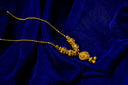 Gold chain with intricate ornate beads and detailed pendant resting on deep blue velvet showcasing fine jewelry art gold.