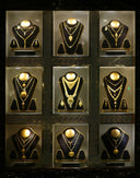 Gold jewelry featuring gold necklaces and matching earrings displayed on black velvet mannequins in illuminated cases