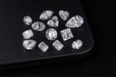 A collection of sparkling diamonds in various shapes on a black surface highlighting art gold and 18k gold jewelry
