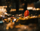 A vibrant red coral gemstone set in a gold-toned ring among sparkling art gold jewelry and fine jewelry pieces.