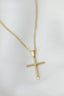A gold cross necklace on a white mannequin