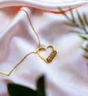 Gold heart necklace with wrapped detail on pink satin