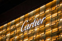 Illuminated white cartier logo on warm gold marble panels highlighting fine jewelry and art gold craftsmanship.