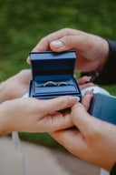 A pair of simple gold jewelry wedding bands in a navy blue velvet-lined box showcasing fine art gold jewelry elegance