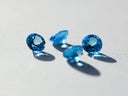 Four vibrant blue faceted gemstones set in 18k gold fine jewelry highlighting birthstone jewelry trends.