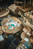 A round wooden basket filled with colorful illustrated pinback badges complementing fine jewelry craftsmanship.