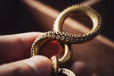 Golden octopus themed keychain with textured ring like tentacles and polished metallic finish inspired by ancient civilizations art gold jewelry