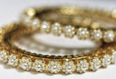 A close up of a stack of gold and diamond bracelets