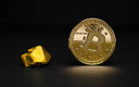 A golden bitcoin coin minted in 2018 with denominations beside an irregular gold nugget in fine jewelry art context