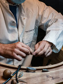 Van Cleef jeweler in lab coat handles fine jewelry components on workbench