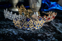 A royal blue and gold tiara with intricate leaf motifs and sparkling gemstones showcasing art gold jewelry craftsmanship
