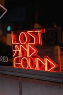 A glowing red neon sign reading lost and found highlights art gold and fine jewelry in historical gold jewelry tales