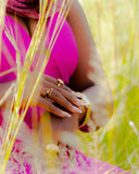 Woman wears jewelry while sitting in tall grass.