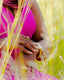 Woman wears jewelry while sitting in tall grass.