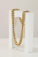 a pair of gold chain bracelets sitting on top of a white box