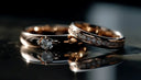 A pair of rose gold 18k gold jewelry diamond rings featuring a central diamond engagement ring and smaller diamonds.